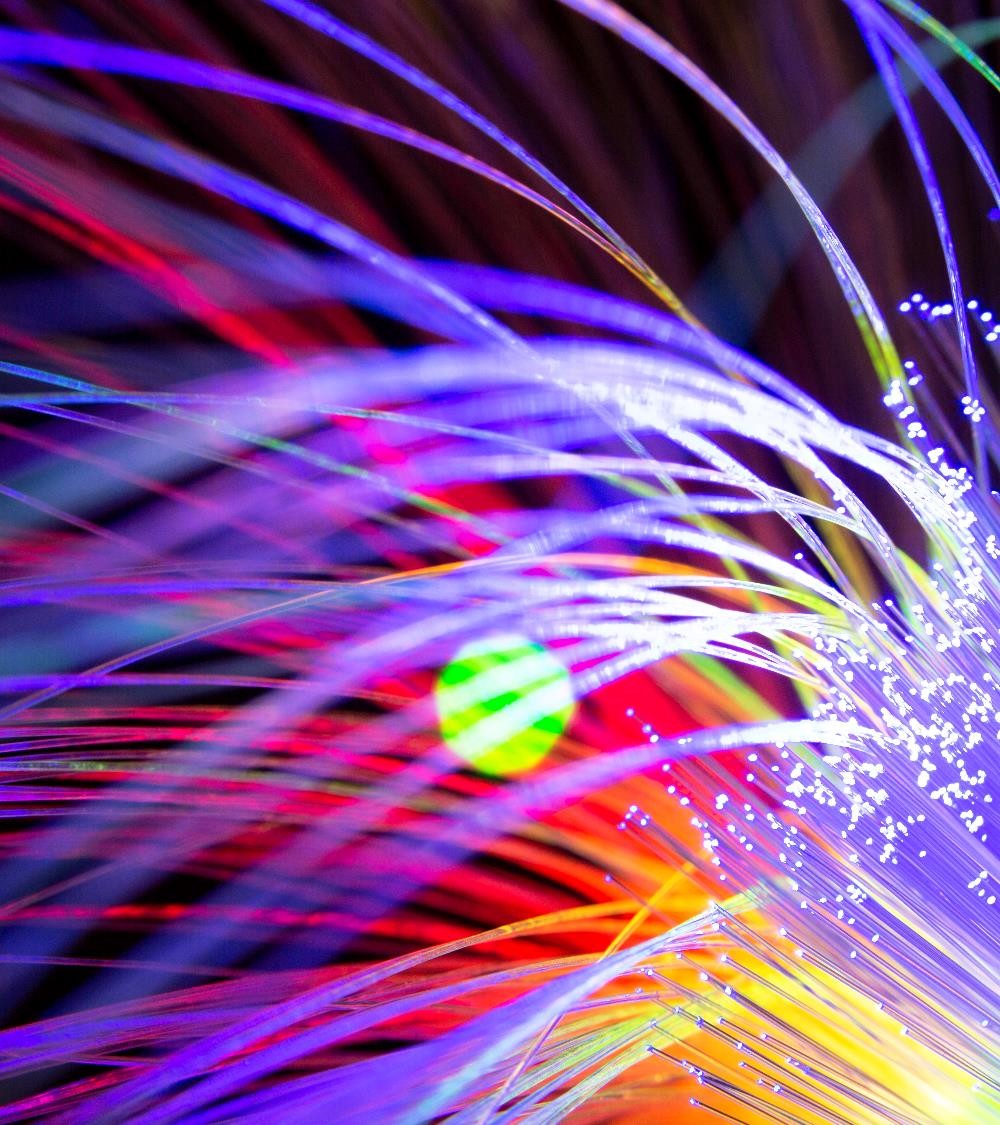 Close-up view of colorful fiber optic strands illuminated with vibrant light, creating a visually striking abstract background.